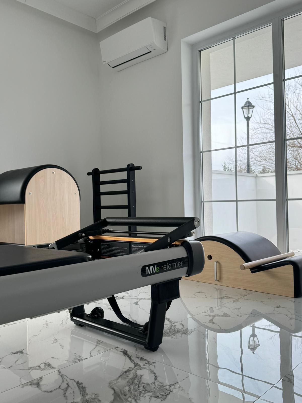 Reformer și ladder barrel în studioul Harmonify Pilates, lângă ferestrele mari